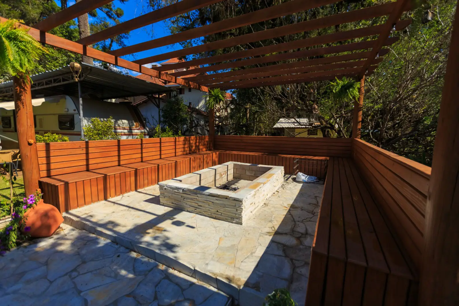 Backyard patio with a patterned concrete surface, pergola overhead and a built-in fire feature