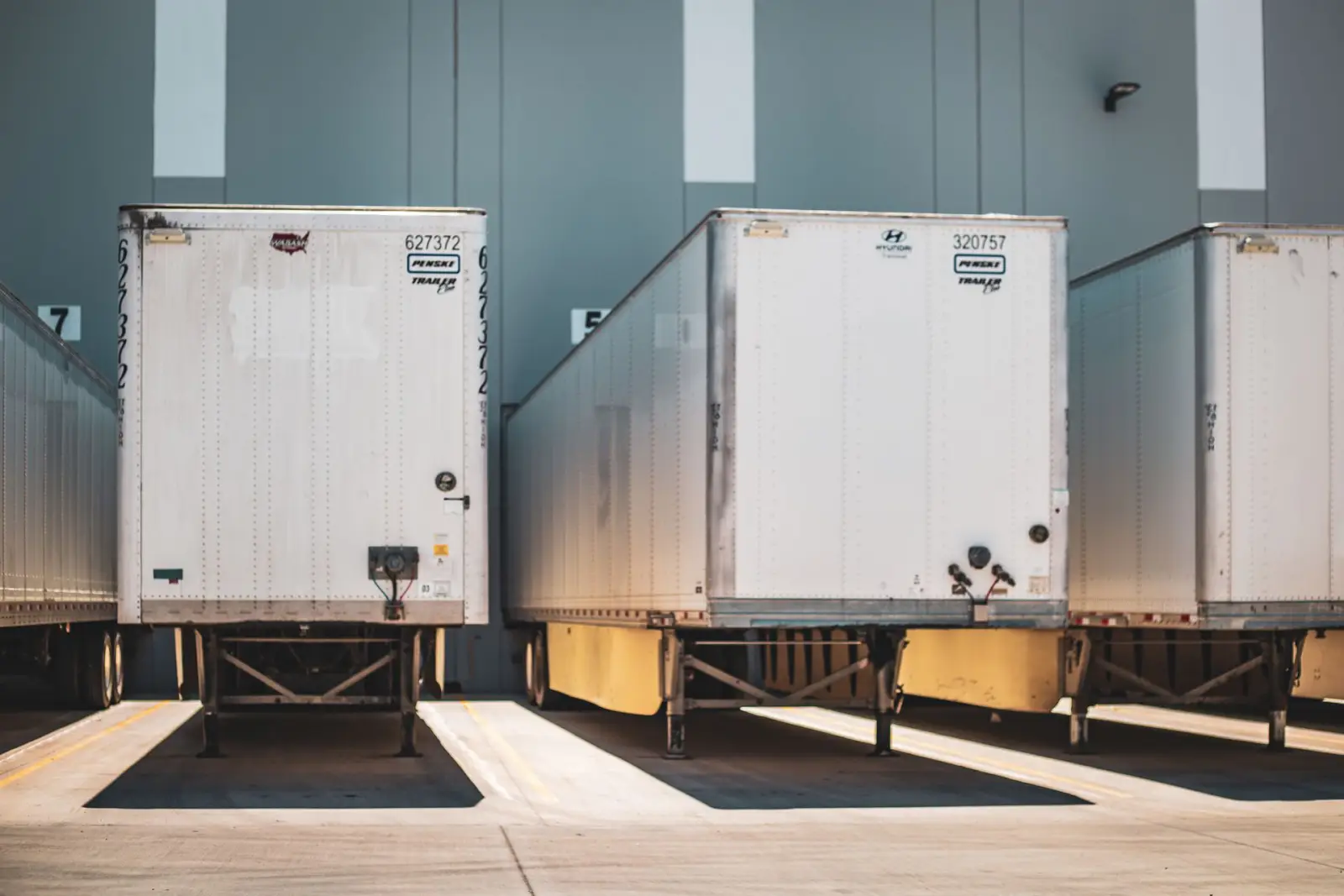 Row of freight trailers backed into a commercial loading dock over heavy-duty concrete pavement