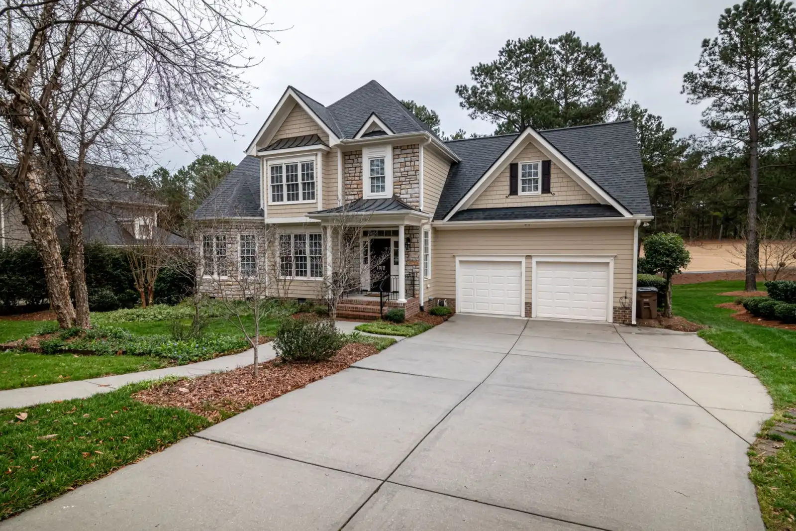 Two-story suburban home with a wide concrete driveway curving to a two-car garage
