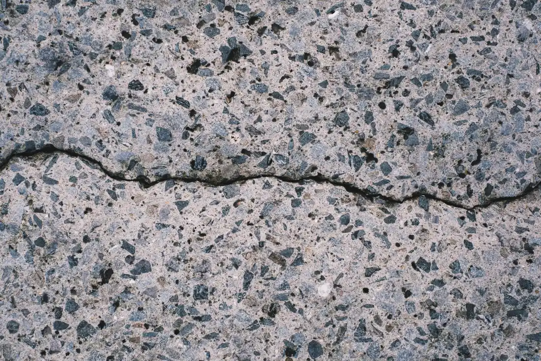 Close-up of a crack through concrete with the aggregate exposed along the broken edge