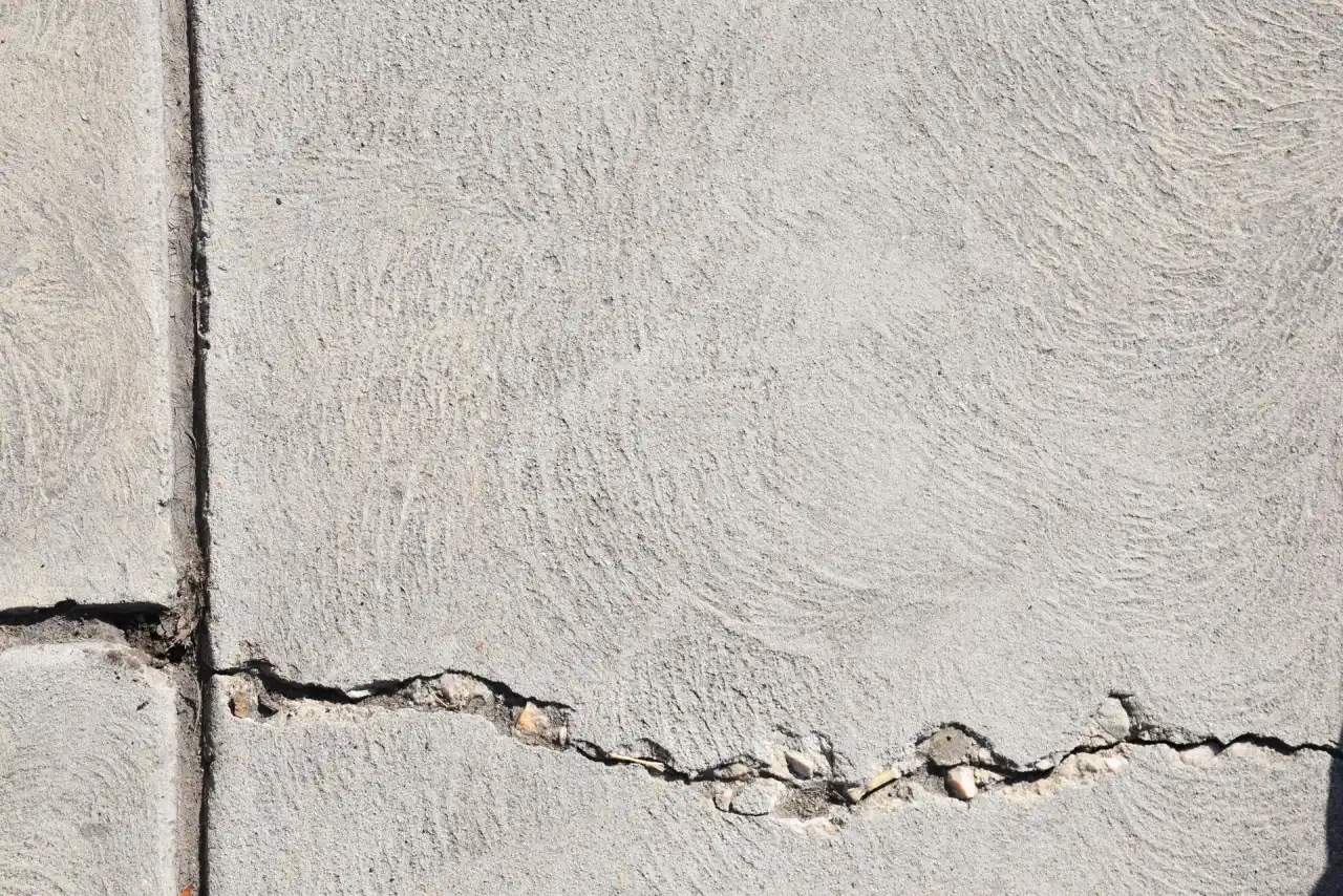 Cracked concrete slab with a crack running out from a control joint across the surface