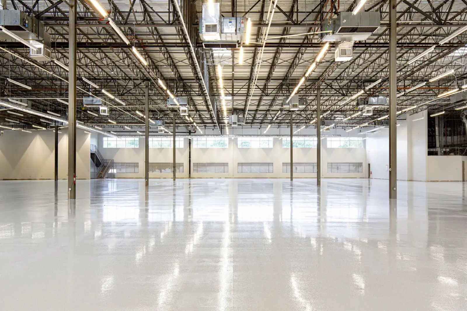 Empty modern warehouse interior with a smooth polished concrete slab floor and steel columns
