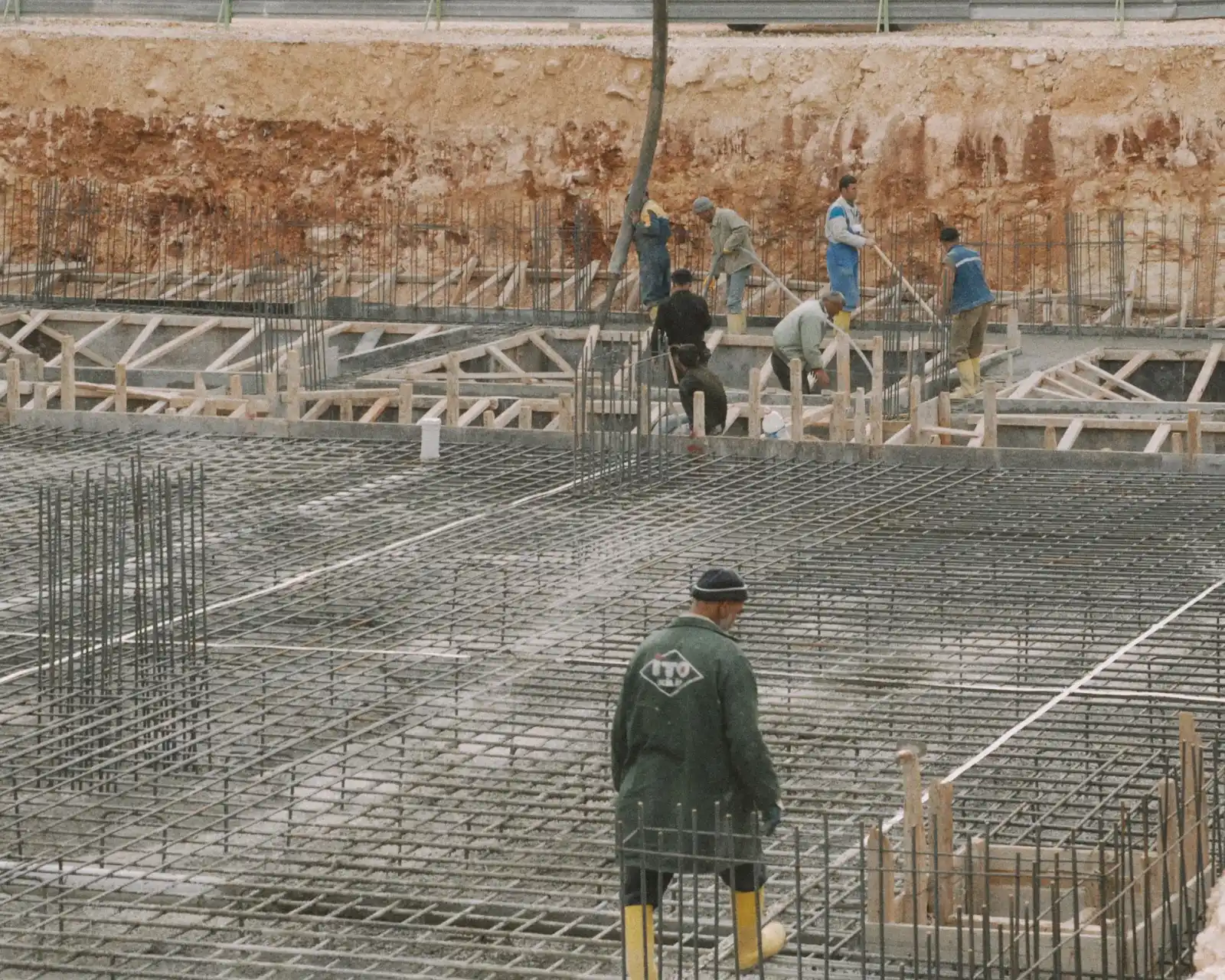 Excavated building foundation with tied rebar mats in place and workers on site