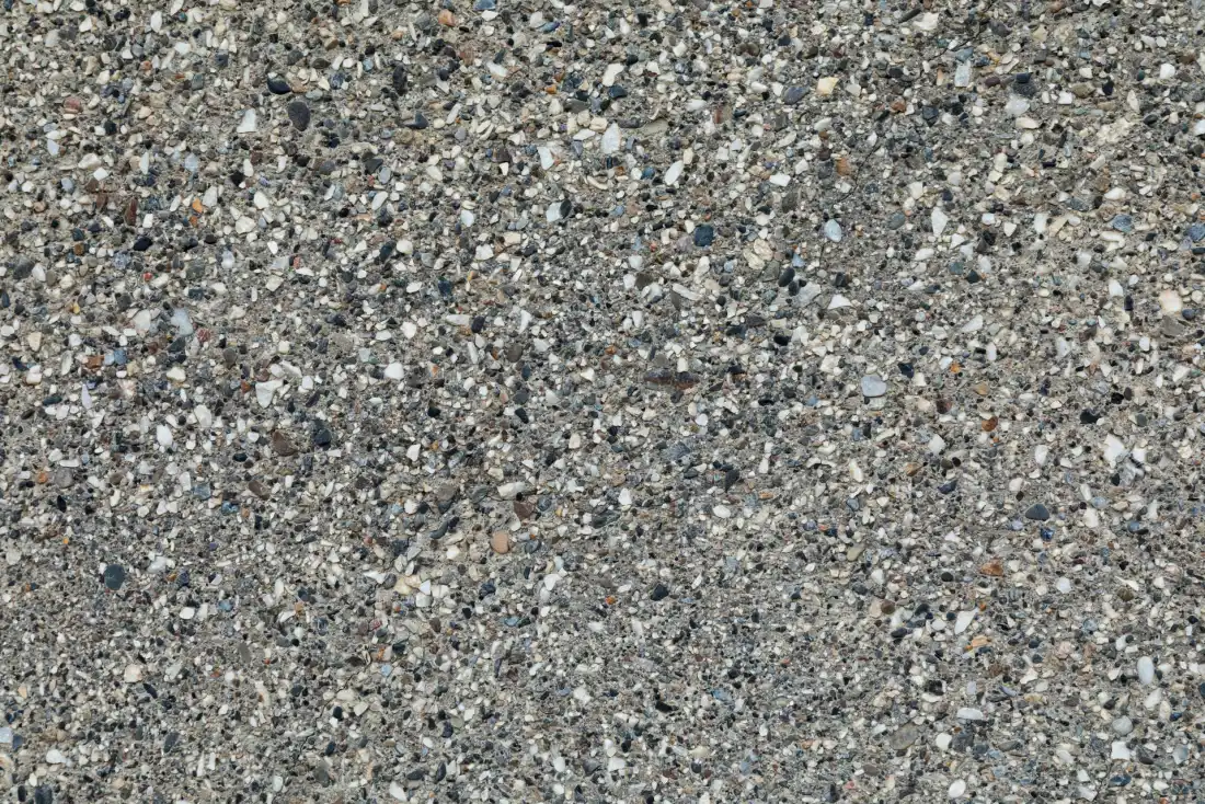 Close-up of a grey exposed aggregate concrete surface with fine speckled stone