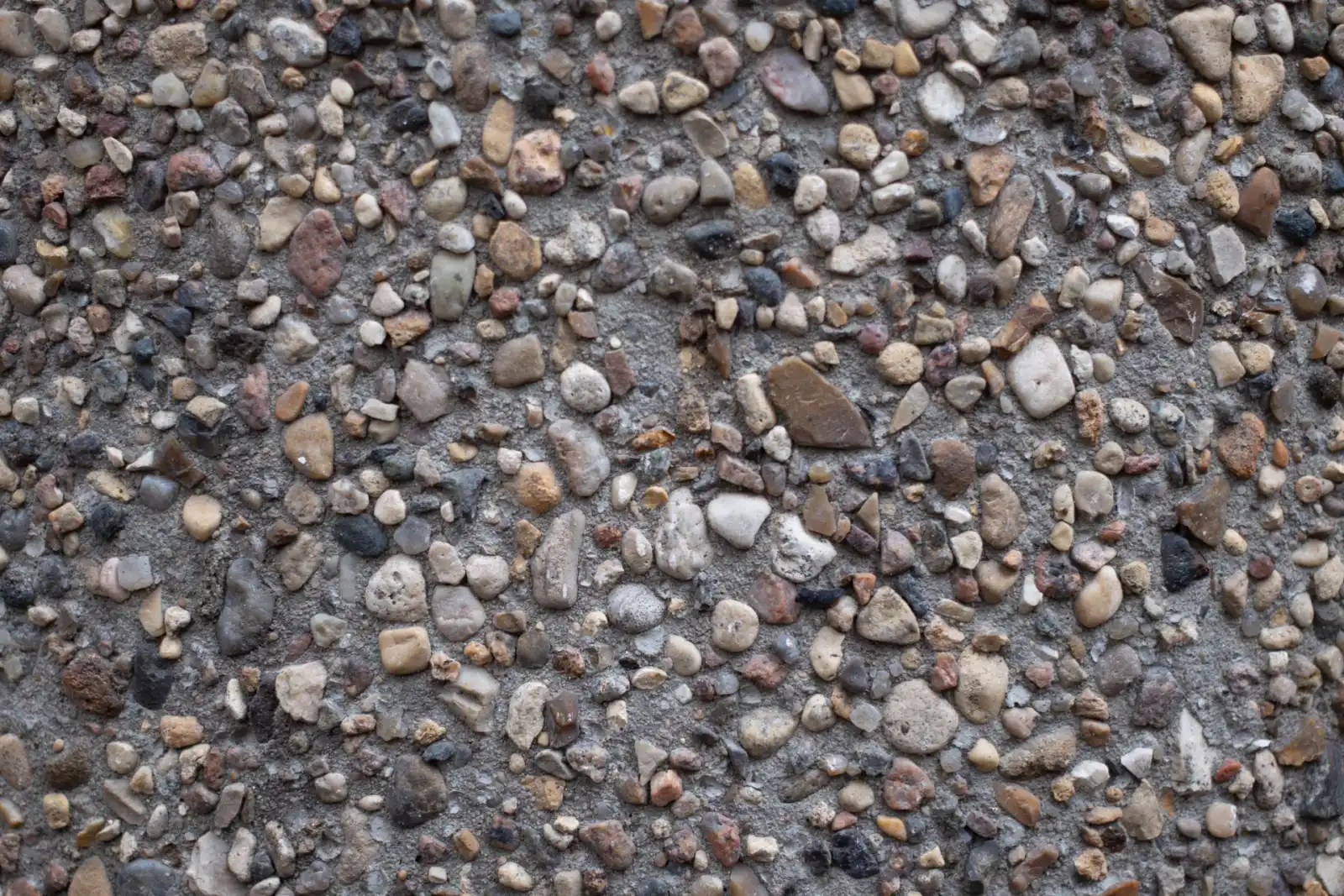 Close-up of a decorative concrete surface with exposed pebble aggregate in warm tones