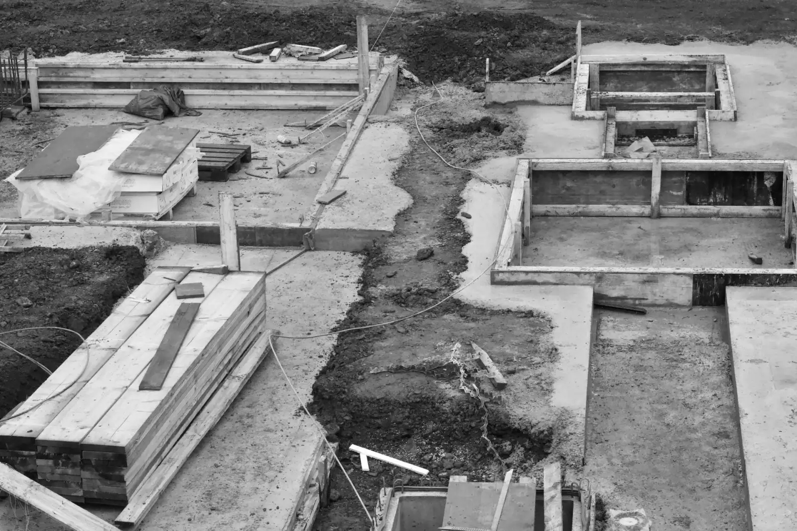 Overhead view of formed concrete strip footings laid out across an excavated building site