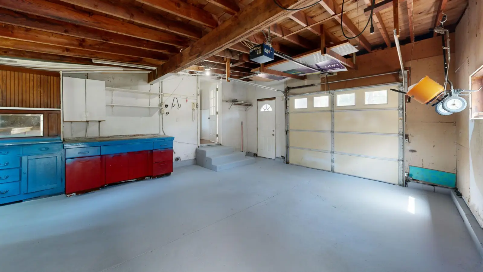 Clean finished garage floor in an open garage bay with storage cabinets along the wall