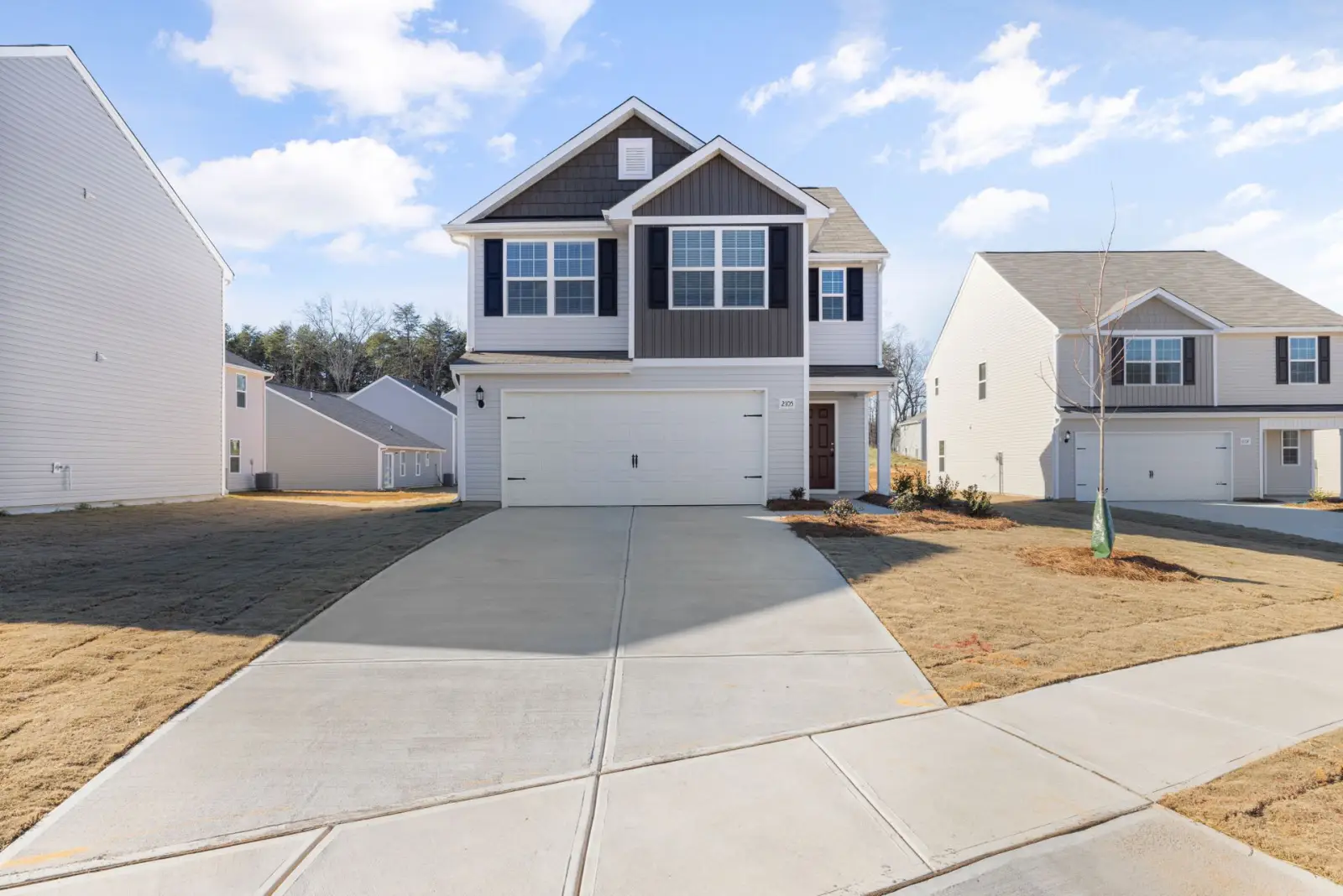 Newly built house with a freshly finished wide concrete driveway running to the garage