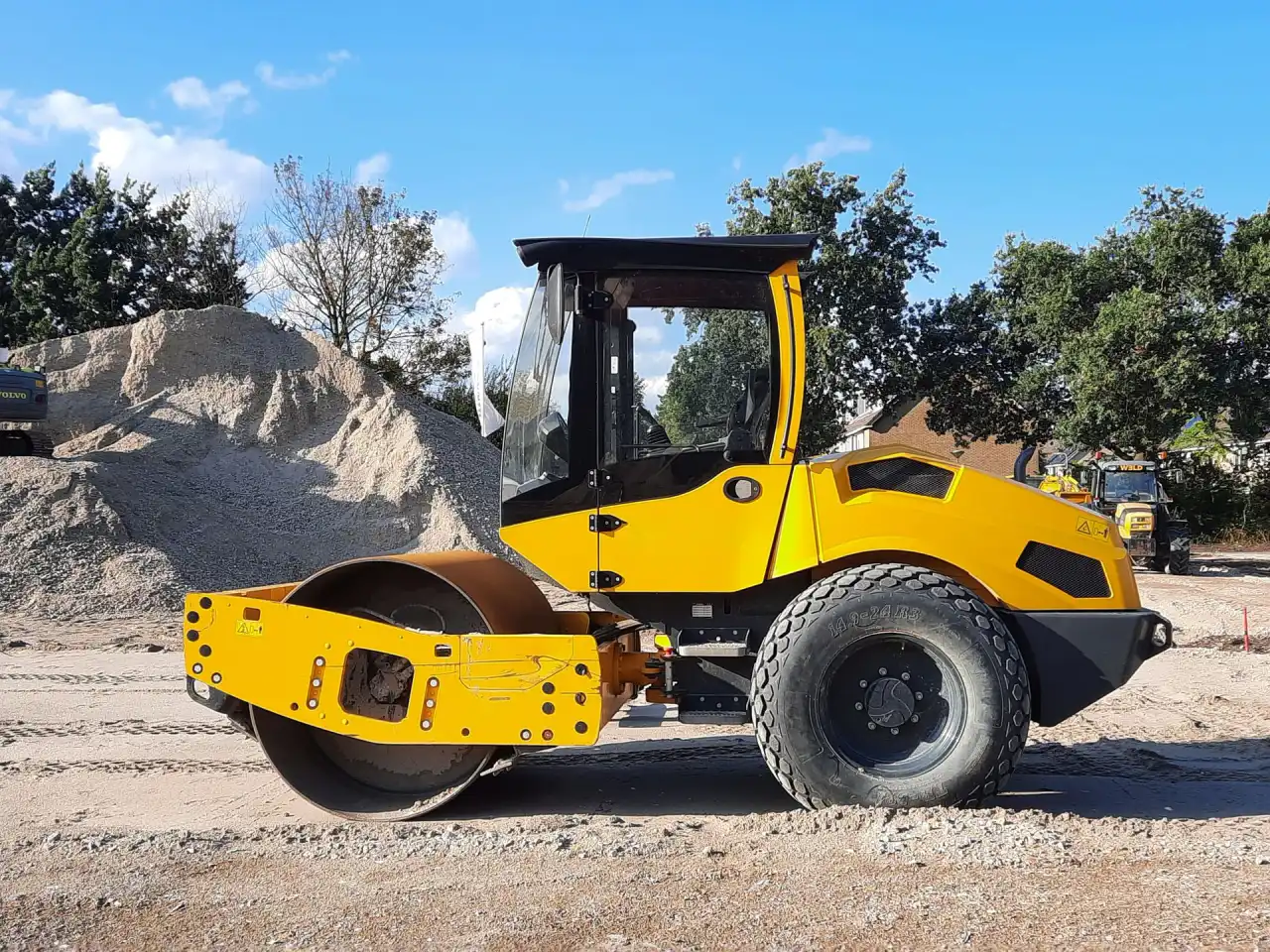 Drum roller compacting the base material across a prepared construction site