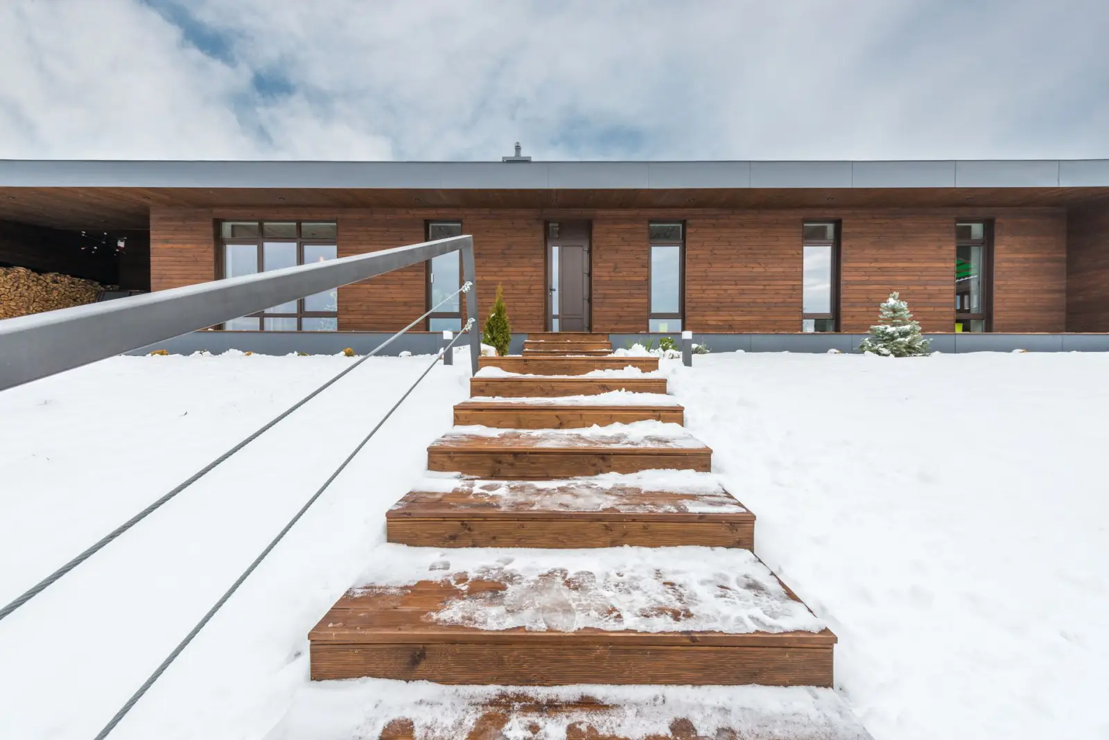 Snow-covered concrete steps leading up to the entrance of a contemporary house in winter