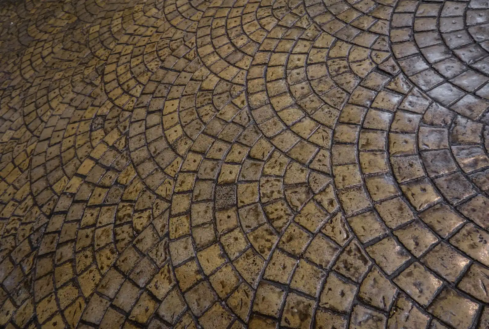 Stamped concrete finished in a circular fan cobblestone pattern with warm brown coloring