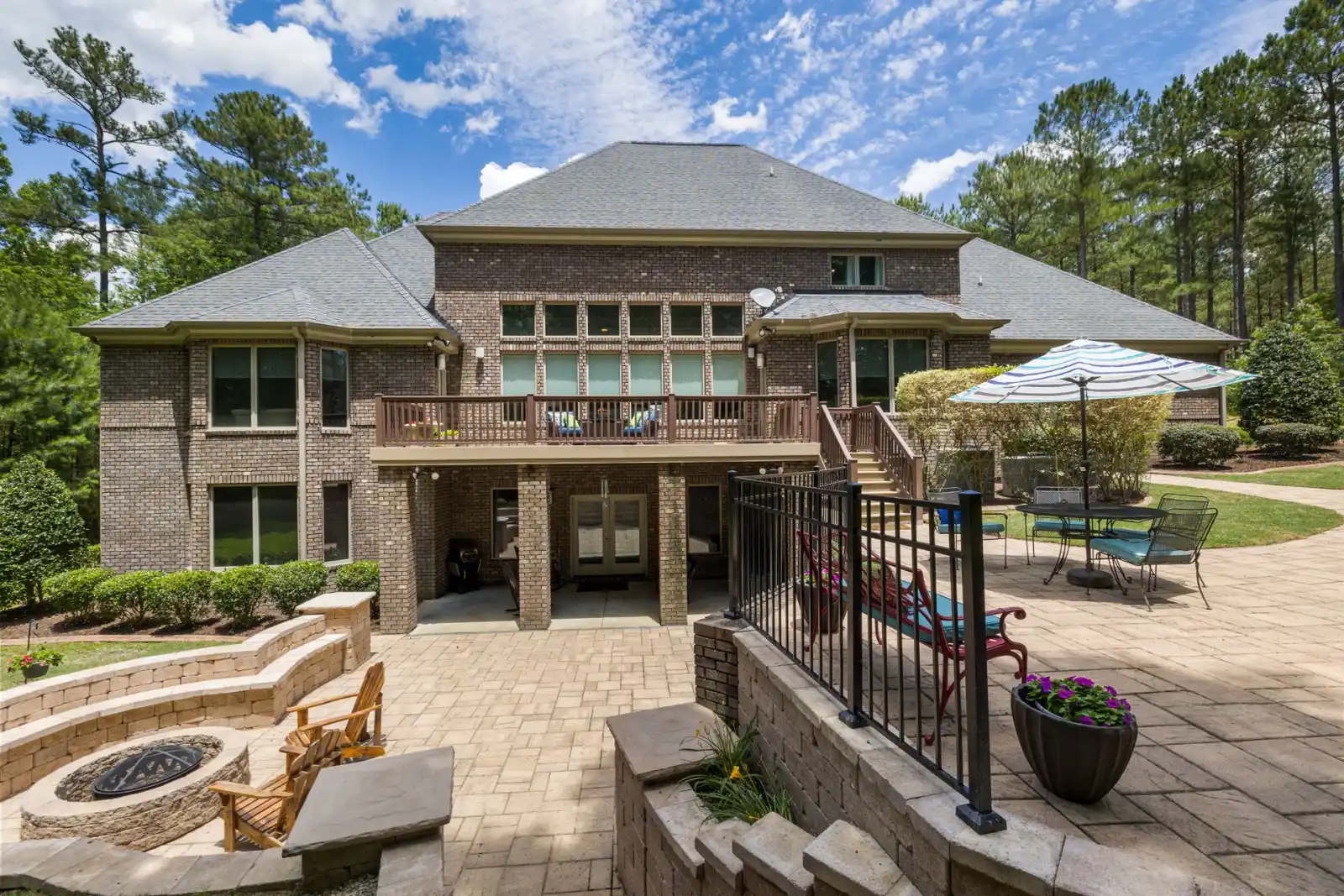 Tiered patio and hardscape with a fire pit and retaining walls behind a large brick house